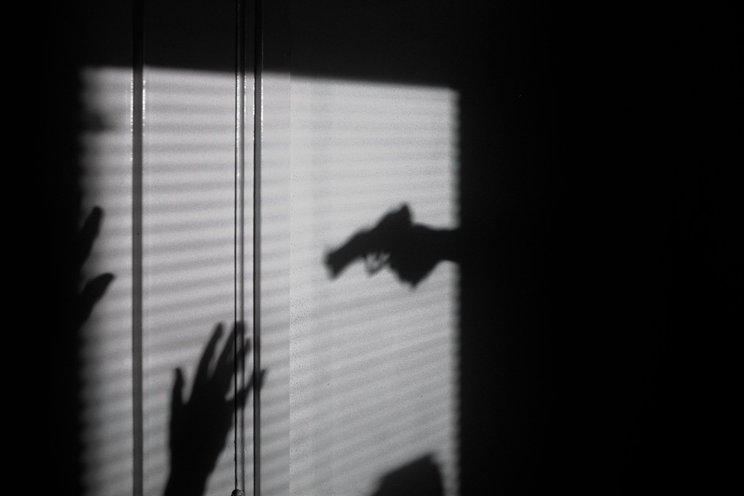 Sombra de persona siendo detenida a punta de pistola